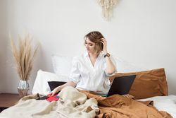 Woman Sitting In Bed Spending Time In Bedroom At Home