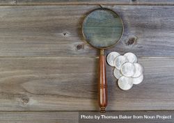 Silver dollar coin collection and old magnify glass on rustic wood 5k3J35