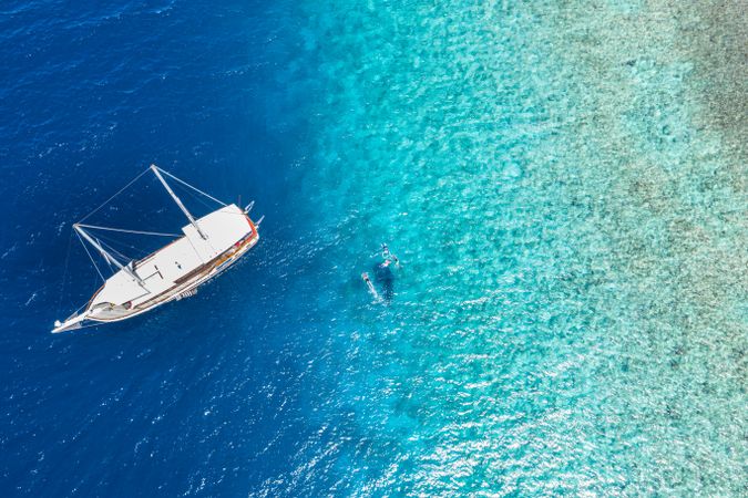 Aerial shot of boat with people swimming in tropical waters