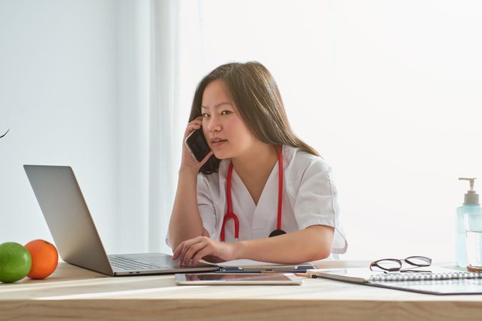Asian doctor having phone conversation on mobile phone in hospit