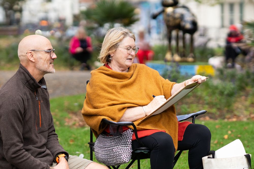 Older female sitting with art teacher during drawing class