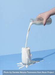 Pouring milk into the glass on a blue background 5aq7a5
