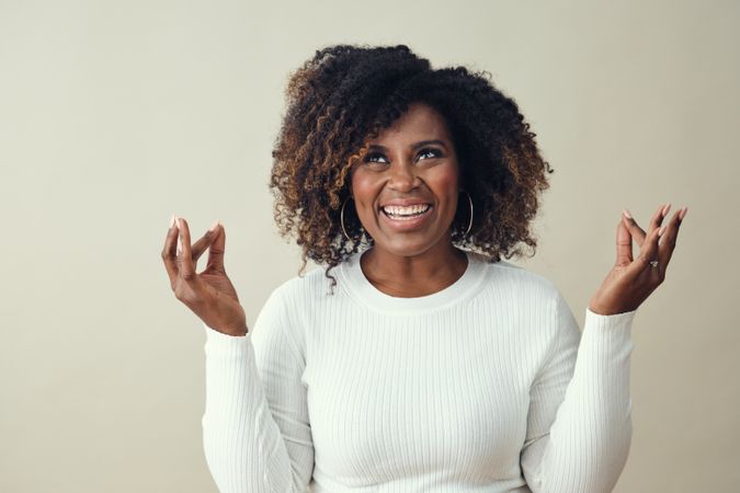Portrait of smiling Black woman with her hands up in meditation gesture and eyes open