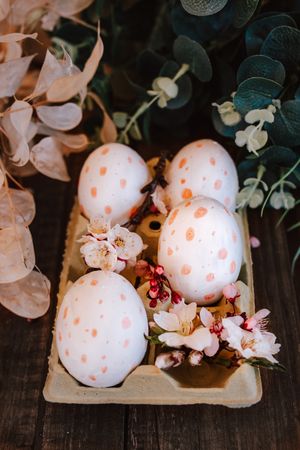 hand-painted easter eggs with pink dots in an egg cup with cherry blossoms