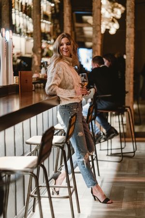Stylish woman drinking wine in bar