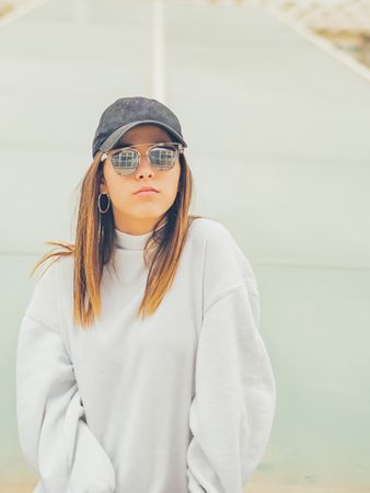 Young woman with glasses standing against wall