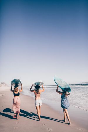Group of young women carrying surfboards at the beach