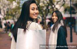 Woman looking back over her shoulder with bag while shopping 0JoPv5