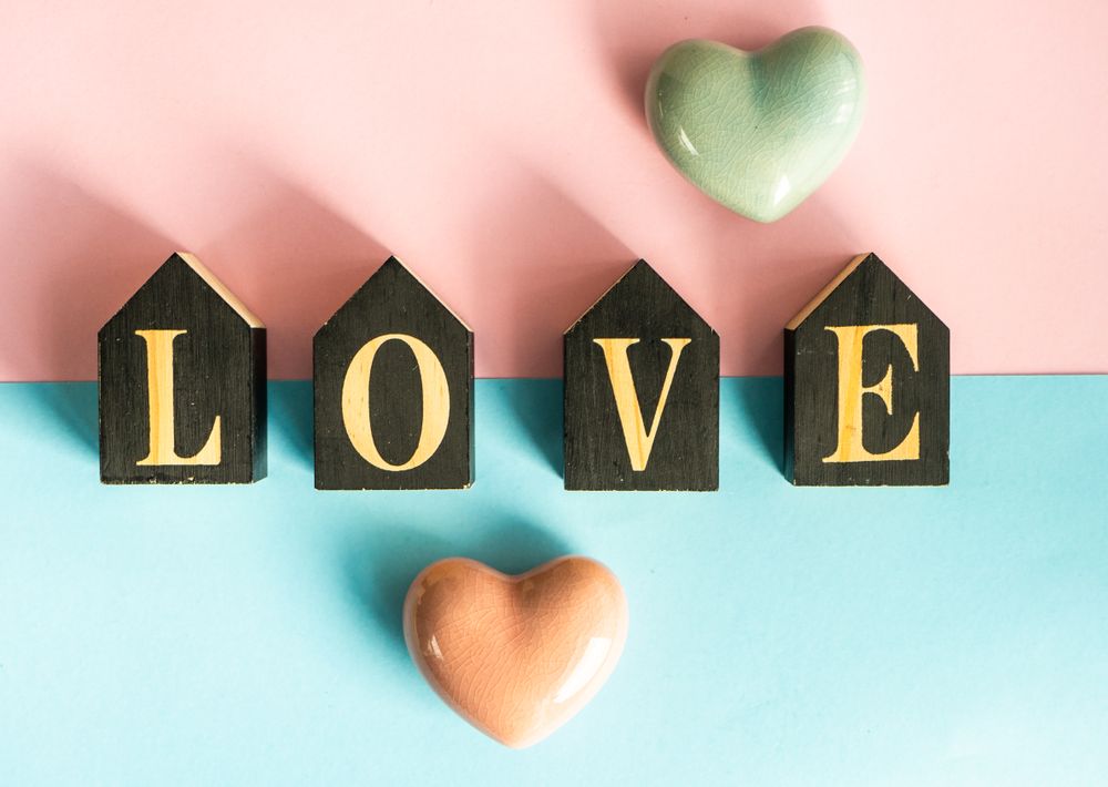 Orange and green heart ornaments on blue and pink pastel table with the word "love"
