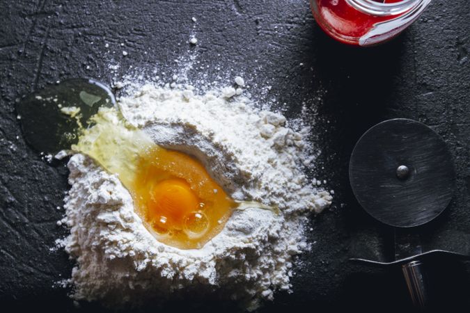 Broken egg and flour on dark background
