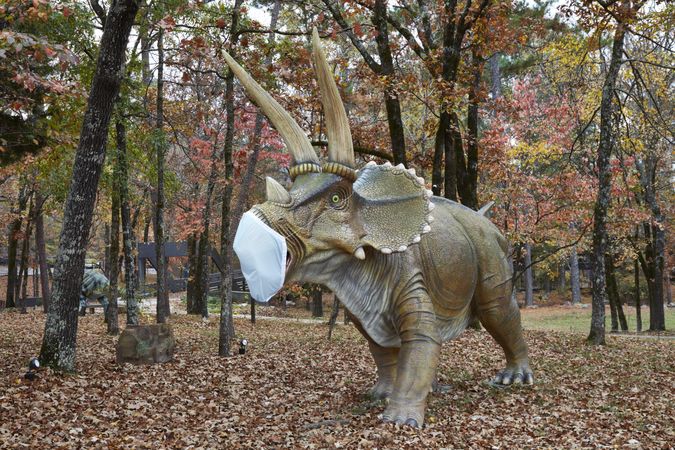 A menacing Triceratops dinosaur figure in a protective mask, AR