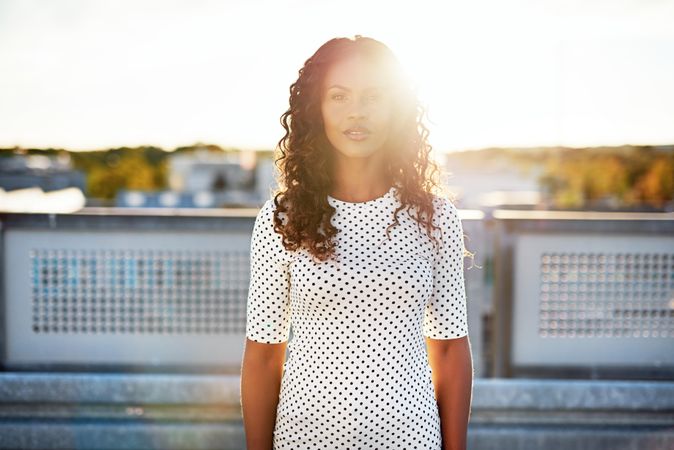 Serious Black woman standing on roof backlit with sun