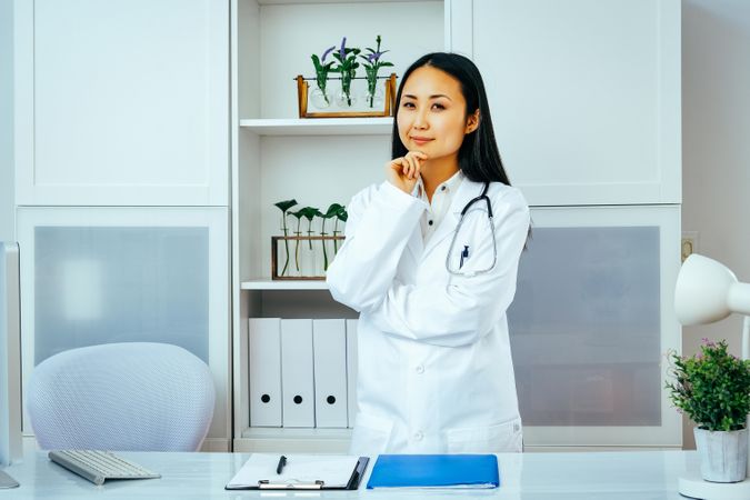 Curious Asian doctor considering something in her office