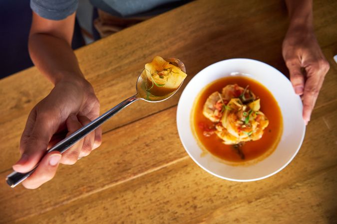 Aerial photo of a person eating with a spoon from a casserole wi