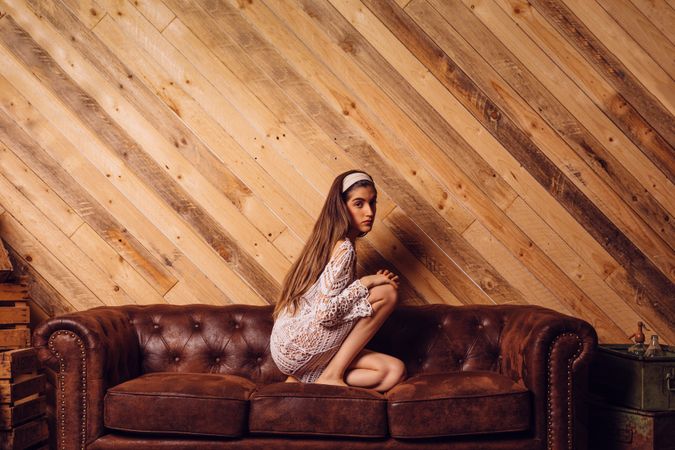 Young woman in white dress sitting on couch
