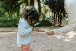 Little girl looking at leaf with magnifying glass