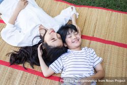 Mother and child laying on picnic throw on grass 4AxYY5