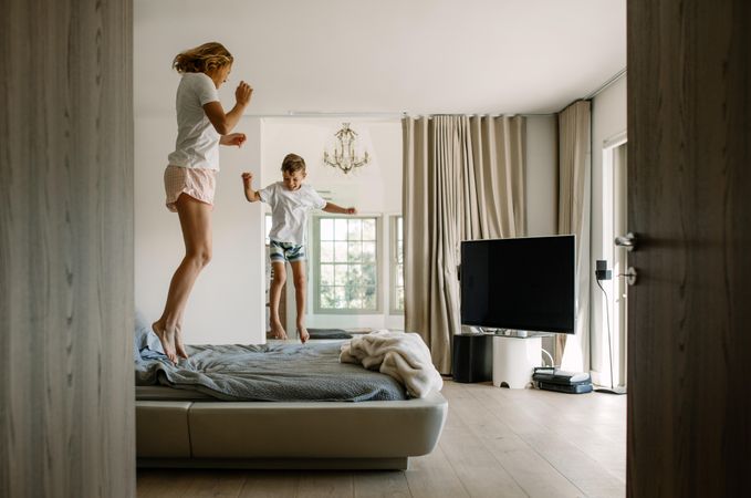 Mother and her little son jumping on bed