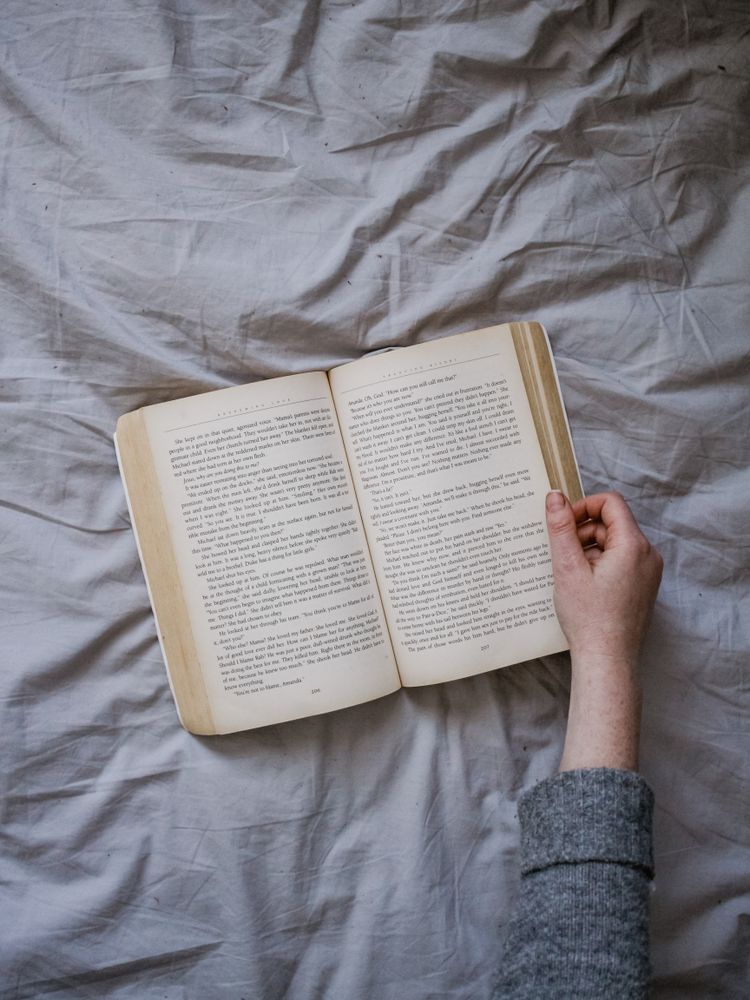 Cropped image of person turning a page of a book on gray textile
