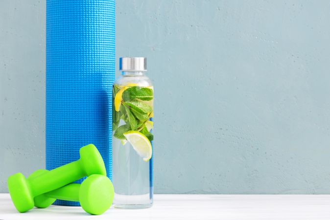 Dumbbells and fresh water with citrus and yoga mat
