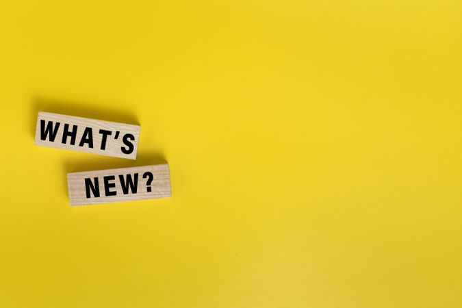 what's new words on wooden blocks isolated on yellow background. copy space