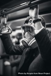 Grayscale photo of person wearing gas mask and suit in train 5r7n14
