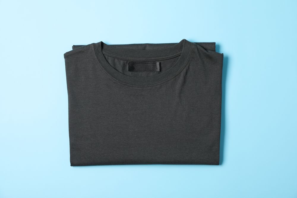 Folded blank t-shirt on blue background, space for text