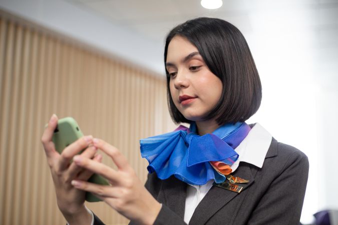 Woman checking mobile phone in flight attendant uniform