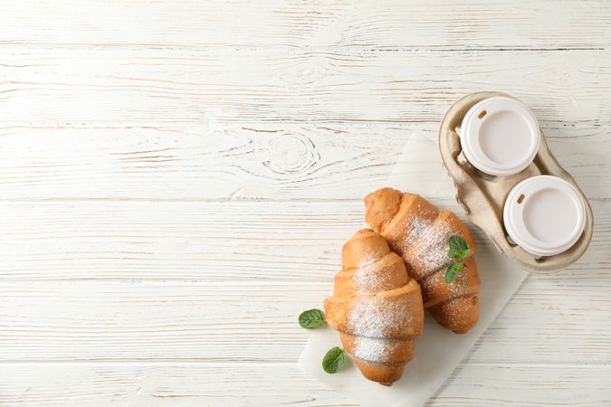 Croissant on wooden table with to go coffee, copy space