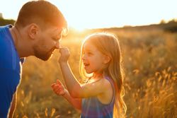 Happy man and daughter  dressed in blue playing in sunny field