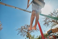 Man swinging on playground in sunlight
