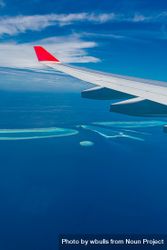 Airplane wing against a blue sky above, and blue sea below 417V80