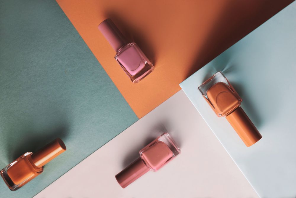 Multi-colored nail polish on pastel colors geometric pattern background