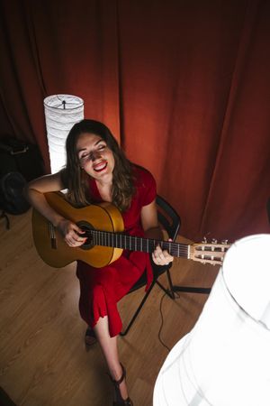 Woman singing and playing guitar on stage in lamplight