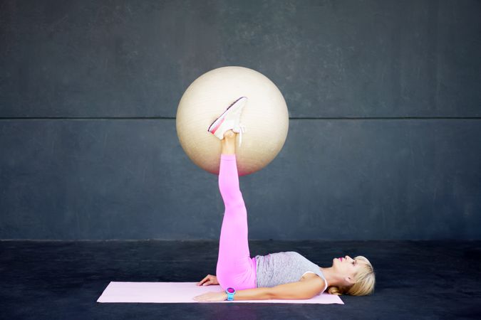 Fit woman doing mat ab workout with stability ball