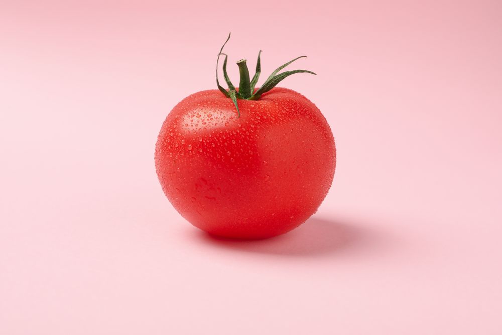 Fresh ripe tomato on pink background, close up