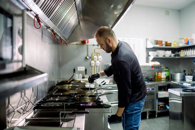 Male chef cooking on frying pan in kitchen
