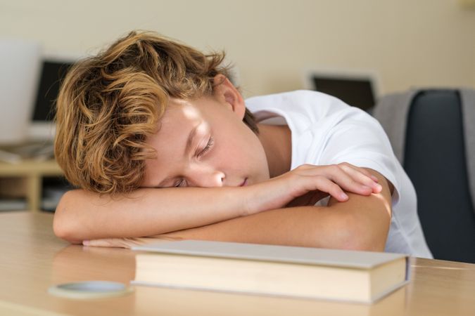 Pupil sleeping on table in classroom