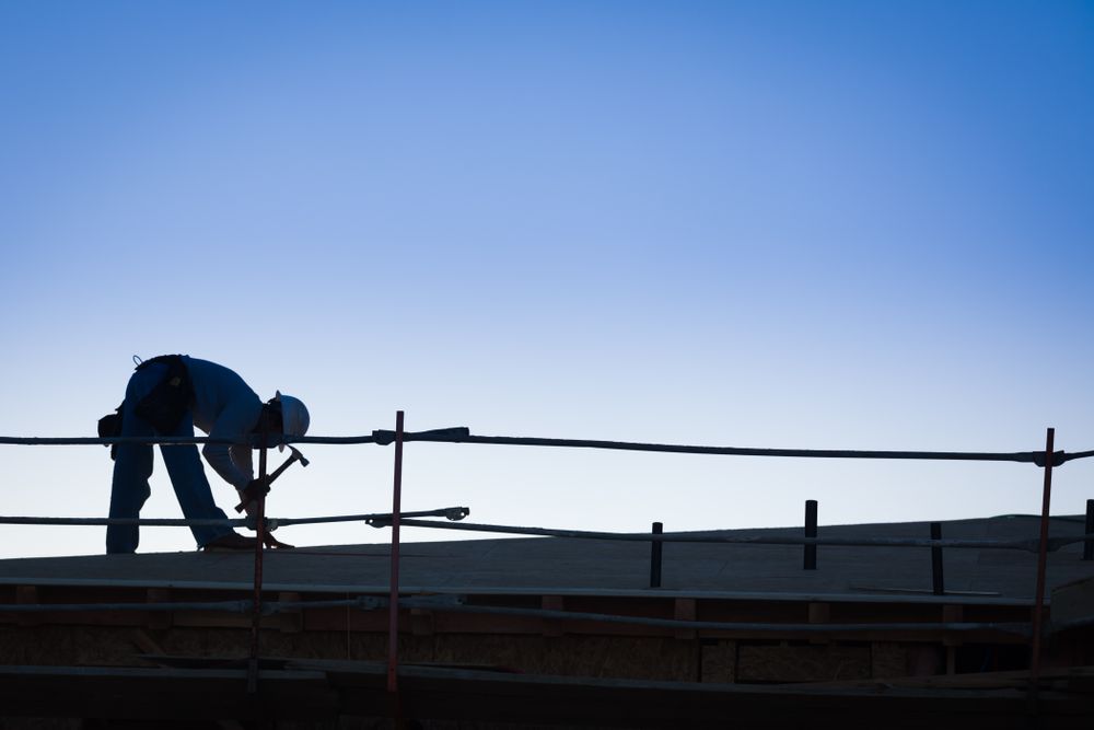 Construction Workers Silhouette on Roof of Building