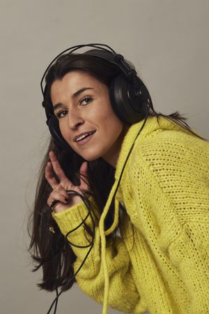 Playful young woman listening to music in studio