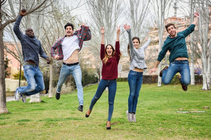 Smiling friends jumping together in park