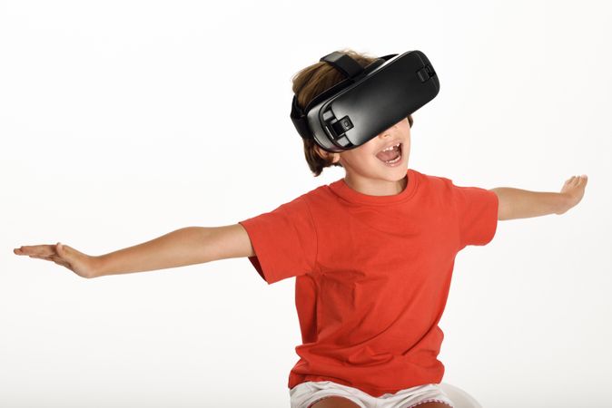 Smiling girl excited by VR glasses and gesturing with arms outstretched