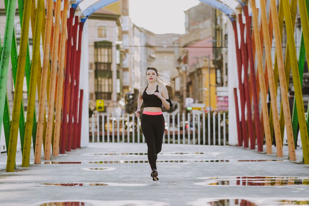Woman with earphones running on street