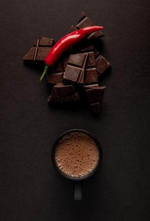 Chocolate near mug with hot drink and pepper