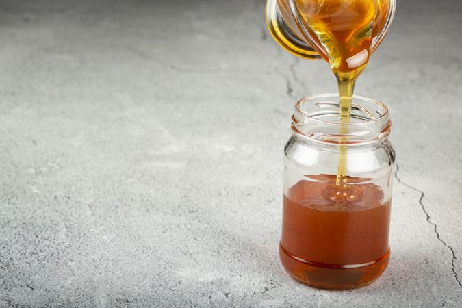 Honey in glass jar on the table.