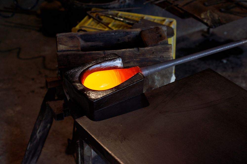 Blowpipe with melted glass in workshop