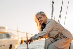 Content older woman with long gray hair leaning on yacht railings
