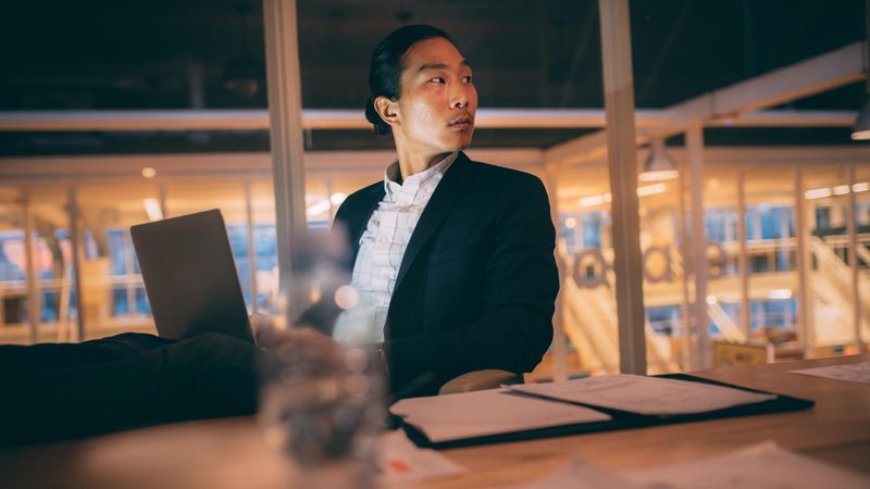 Asian businessman sitting late night in office working on laptop