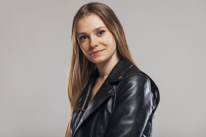 Blonde woman with leather jacket posing in studio