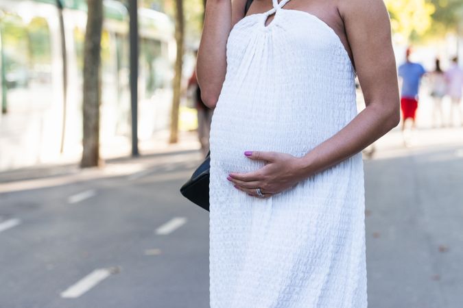 Anonymous pregnant woman in long white dress